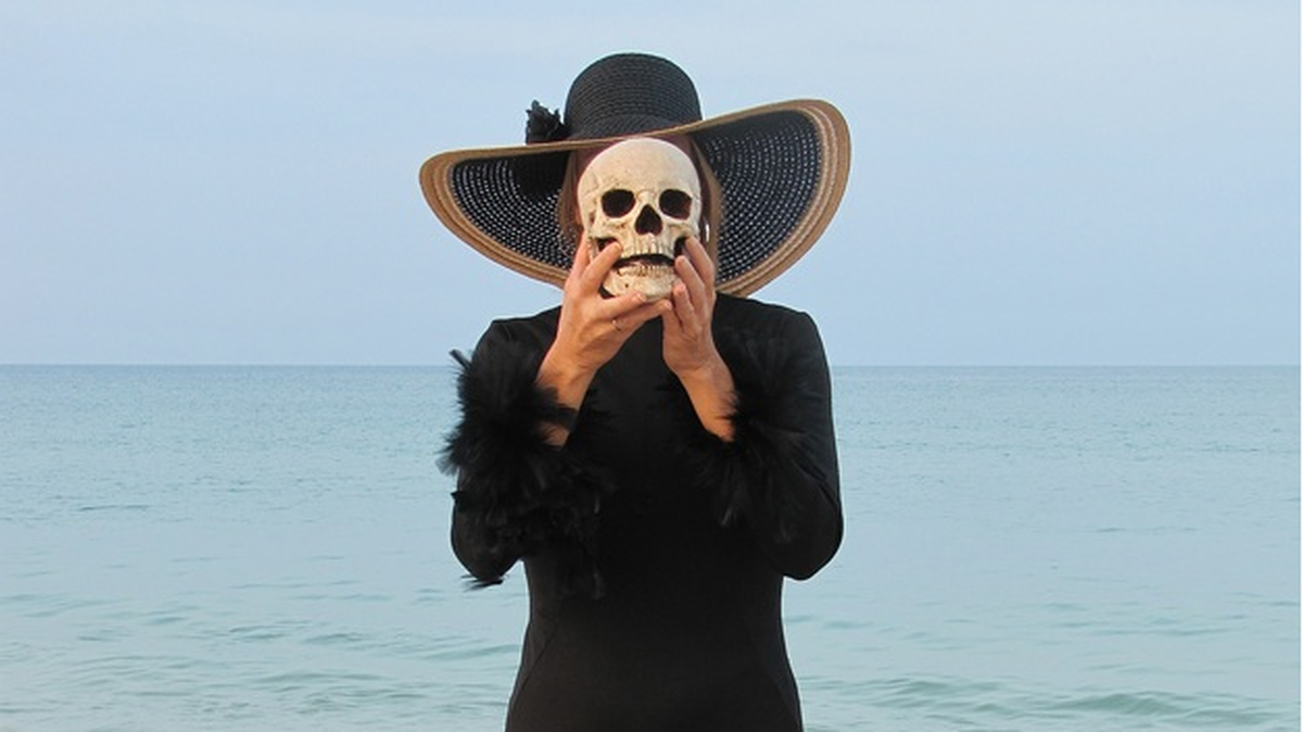 A photograph from Jonathan Brooks' Skulls Collection featuring a peaceful beach contrasted with dark figure holding a skull.