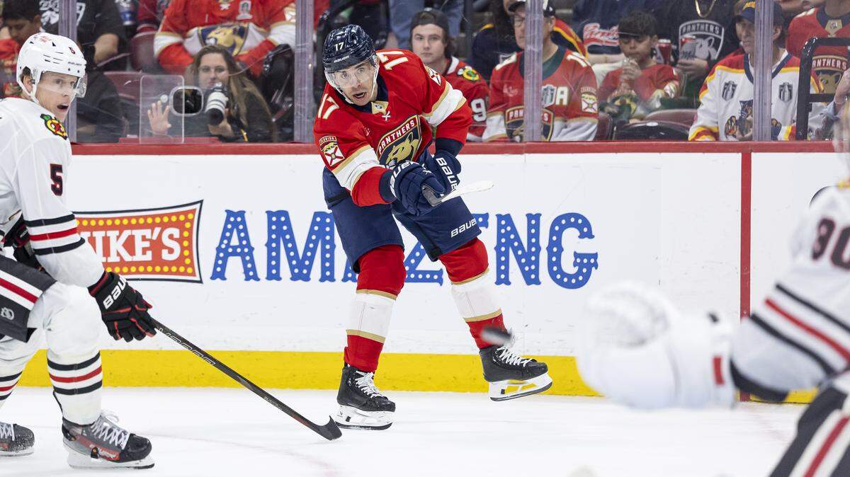 Florida Panthers center Evan Rodrigues (17) takes a shot toward Chicago Blackhawks goaltender Spencer Knight (30) as defenseman Connor Murphy (5) defends in the second period of their NHL game at Amerant Bank Arena on Tuesday, Oct. 7, 2025, in Sunrise, Fla.