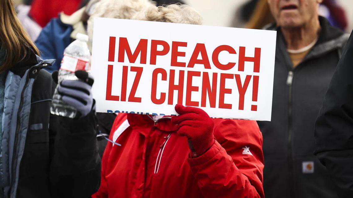 In January, a woman holds a sign targeting Rep. Liz Cheney, a Wyoming Republican, as Rep. Matt Gaetz speaks to a crowd during a rally against her in Cheyenne.