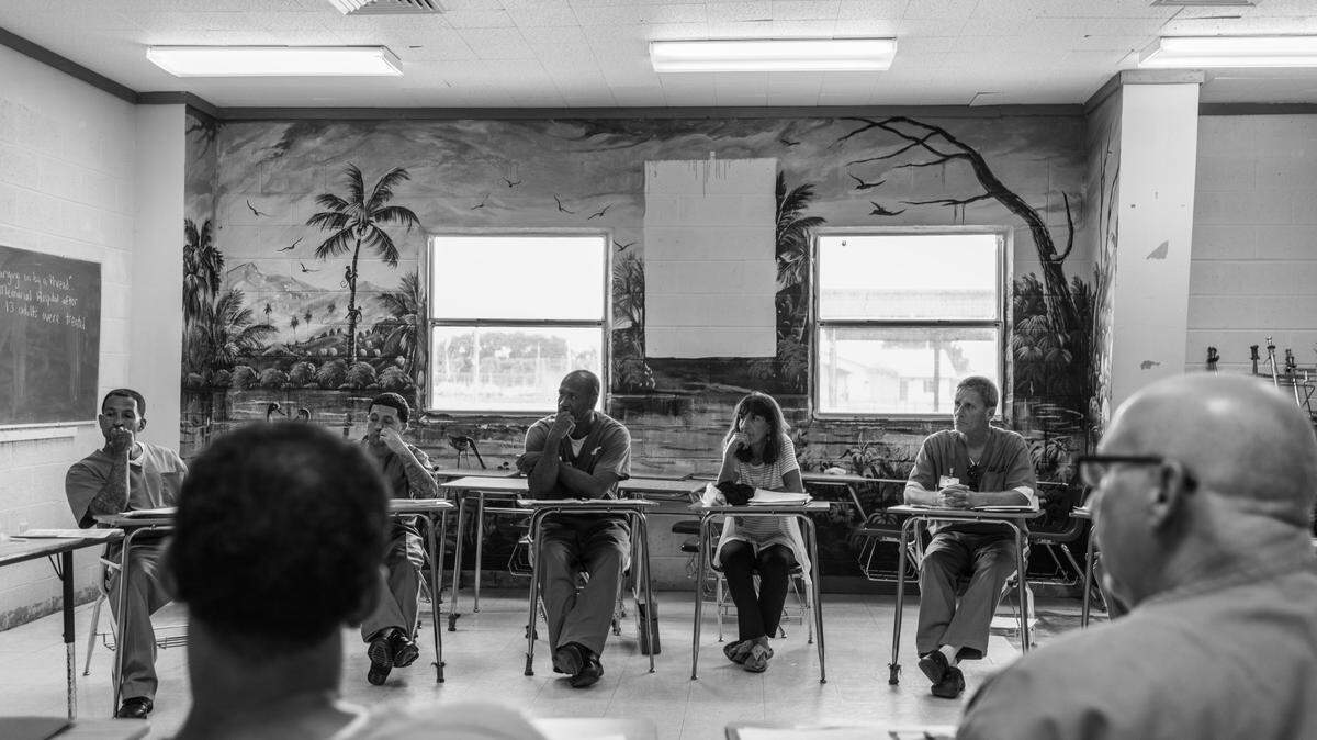 Kathie Klarreich, executive director of Exchange for Change, center, sits in a class with students.