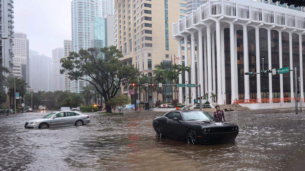 A driver stands next to his Dodge after his car got stuck as Tropical Storm Eta slammed into Miami, flooding several parts of the city in early November 2020.