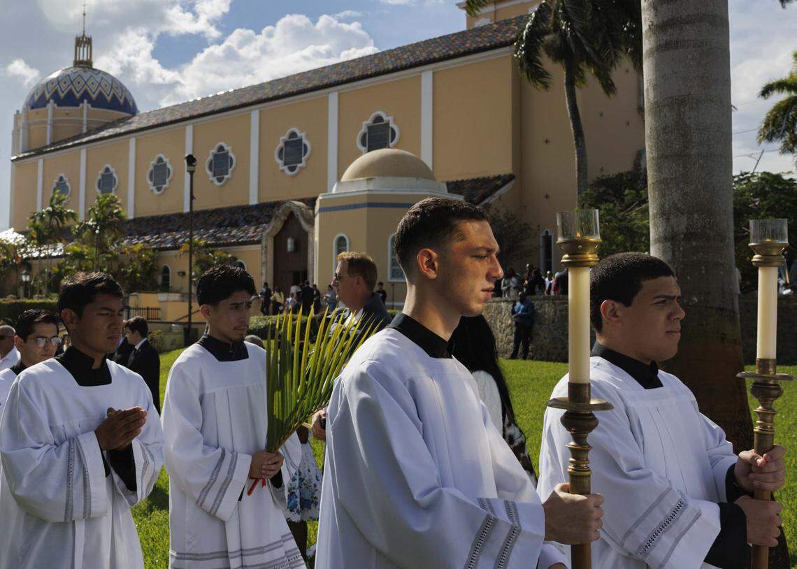 Alter servers process past the crowd towards the cathedral after the traditional blessing of the palms before Palm Sunday Mass on Sunday, March 29, 2026, at the Cathedral of St. Mary in Miami, Fla.