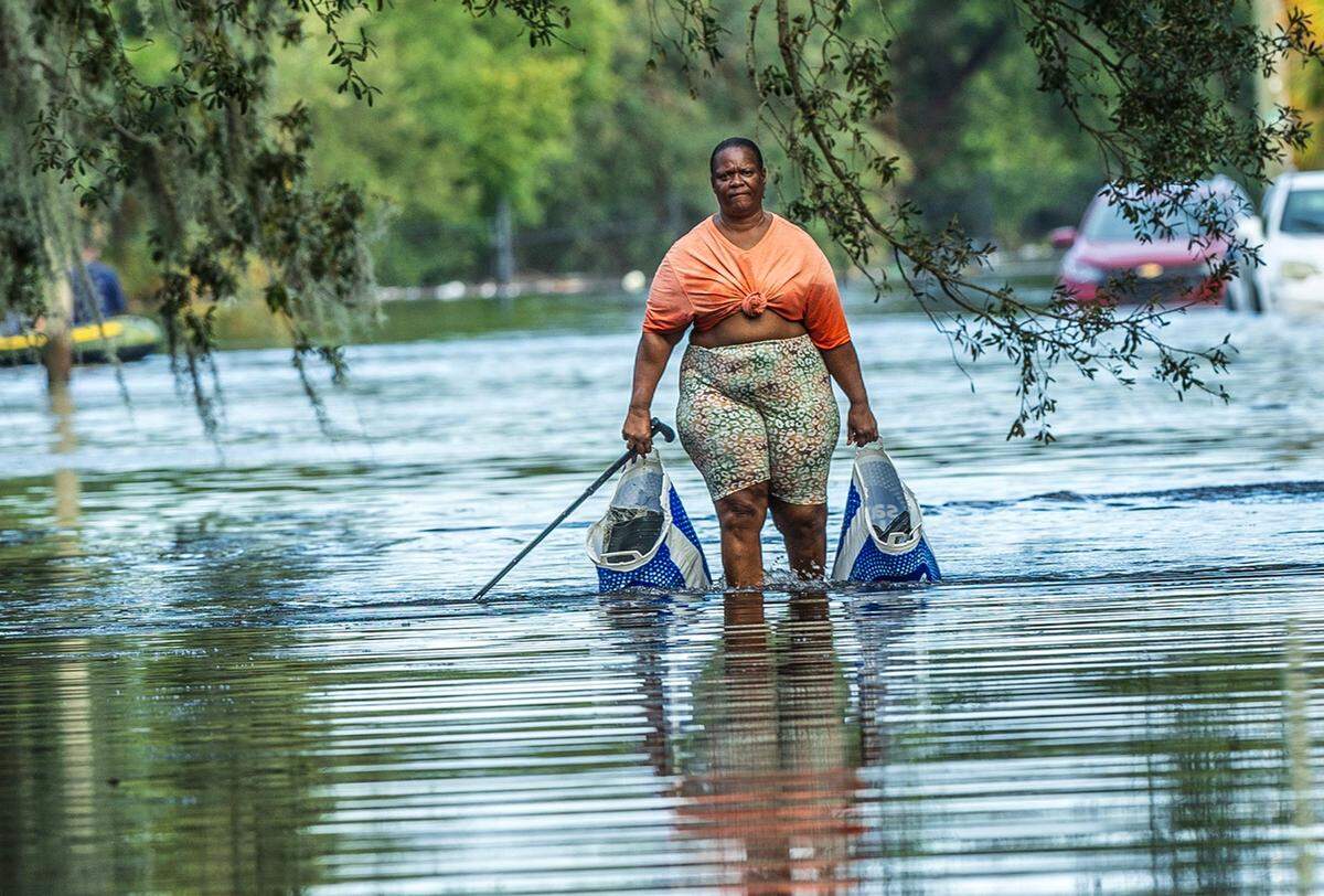 A resident walks with her belongings through the flooded N 15th St in North Tampa, on Thursday, October 10, 2024, a day after Hurricane Milton crossed Florida’s Gulf Coast.