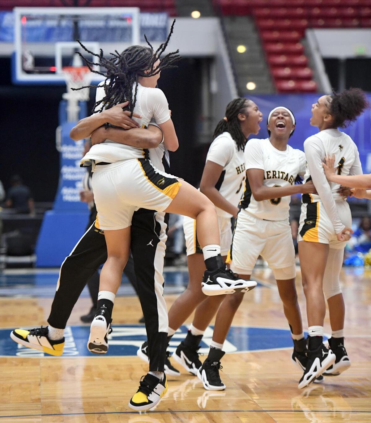 American Heritage’s Jasleen Green (34) jumps into the arms of one the coaches after the Class 5A final against Mainland as other players celebrate during the Florida High School State Championships at the RP Funding Center in Lakeland, Fl on Friday March 8, 2024. American Heritage defeated Mainland 60-55 to win the Class 5A State Title.