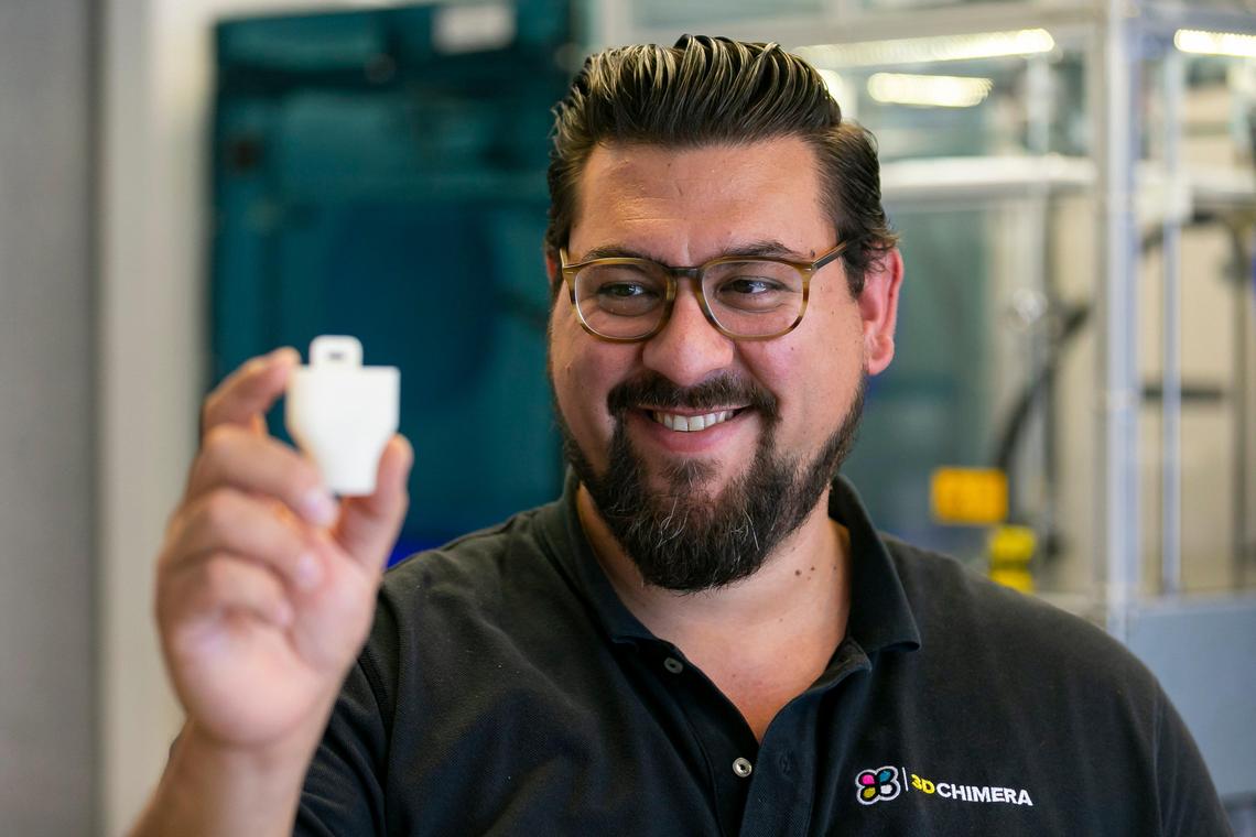 Alexander Hussain, 37, the co-founder of 3D Chimera, holds an adapter piece for a COVID-19-proof snorkle mask after he 3D-printed it at his office in Miami, Florida, on March 1, 2020. Hussain is planning to sell the adapter piece and face shield to local hospitals to keep workers safe from the coronavirus.