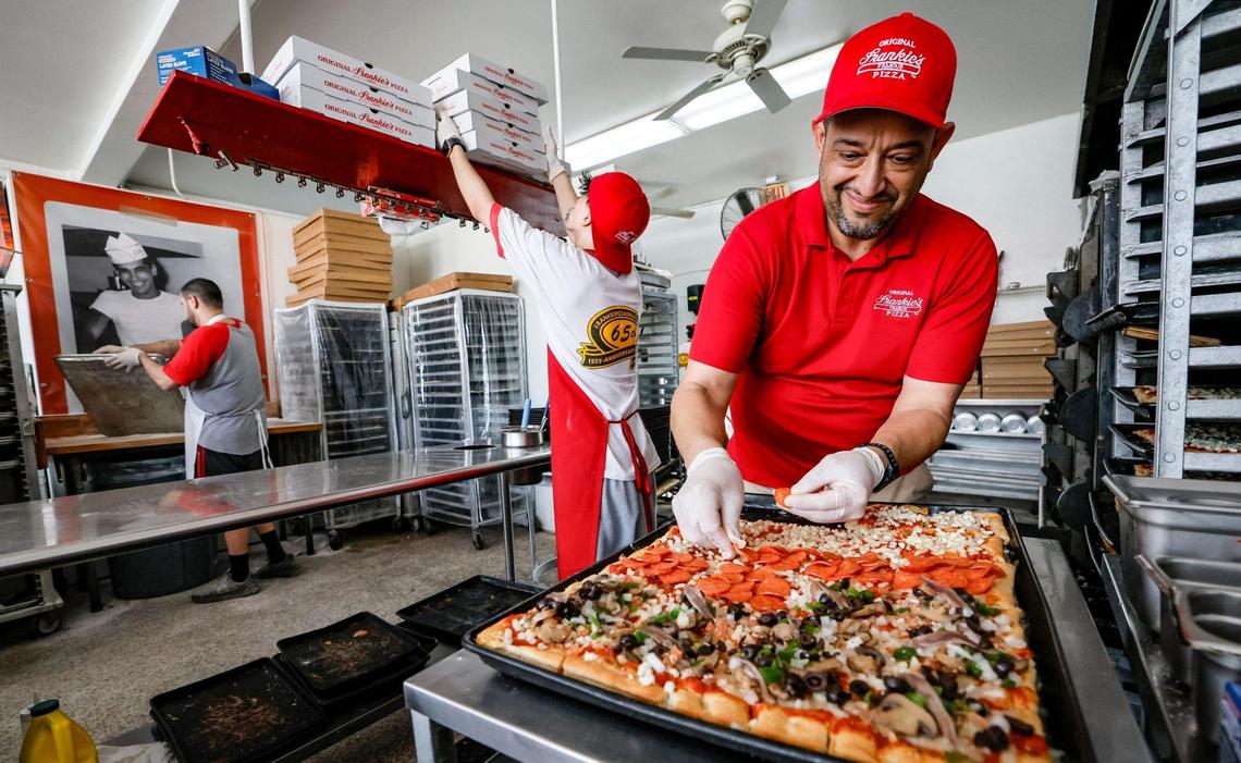 El gerente José Delgado, agrega ingredientes a las pizzas antes de colocarlas en el horno en Frankie’s Pizza en Miami.