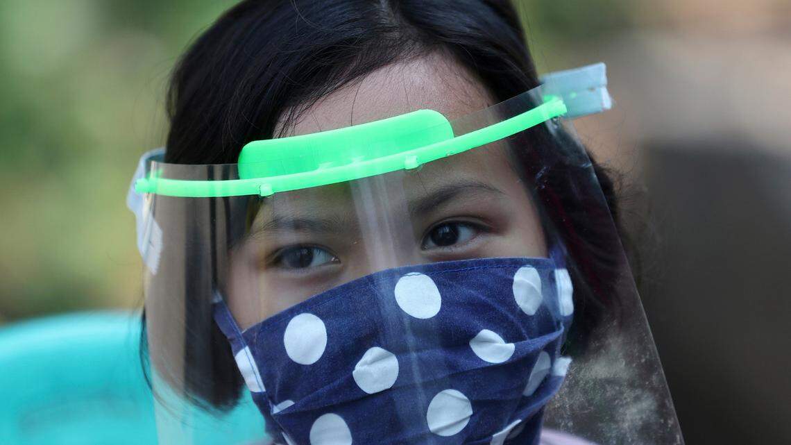 A child wears a face mask and shield as a precaution against the new coronavirus at a community health center in Tangerang, Indonesia, Tuesday, May 12, 2020. (AP Photo/Tatan Syuflana)