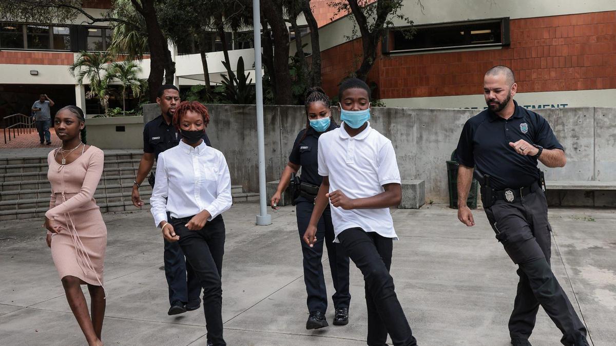 Telrica Williams, 14, left, Tacora Bryan, 16, Miami Police Officer Nick Perez, right, follow the lead of Tyquane Hankerson, 14, center, as they perform a dance for TikTok outside of the Miami Police command center. The students were there as part of Teen Talks, a program aimed at improving relationships between Black youth and police officers.