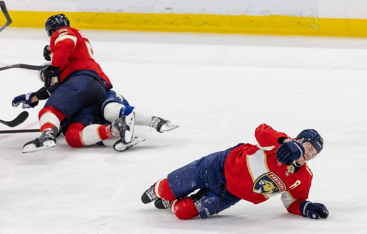 Matthew Tkachuk (19) lies injured on the ice after a hit from Tampa Bay Lightning right-winger Nikita Kucherov (86), while Florida defenseman Aaron Ekblad (5) retaliates during the first period of an NHL game at Amerant Bank Arena, Sunrise, Florida, on Monday, December 23, 2024.