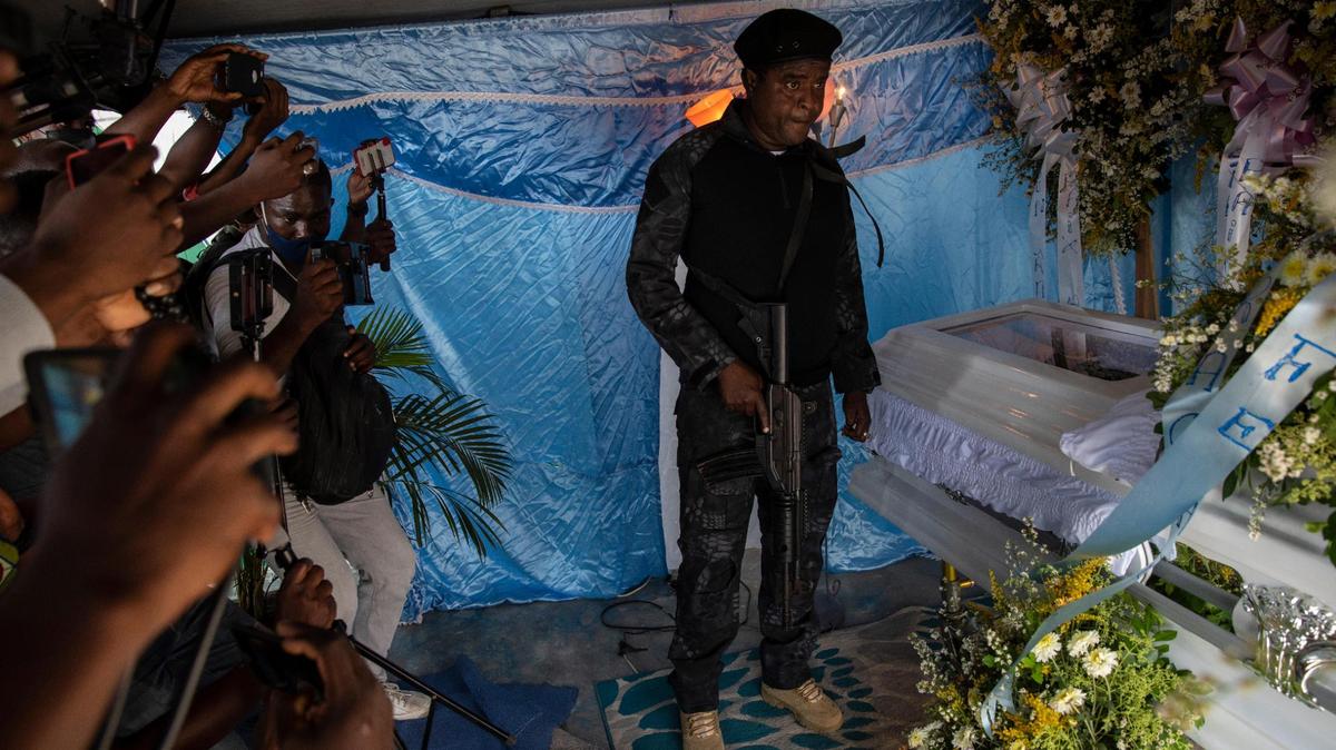 Jimmy Cherizier, aka Barbecue, a former policeman who leads the G9 gang coalition, holds a weapon as he stands next to the coffin containing the remains of Tonino Manino, one of his lieutenants, during a funeral service in Port-au-Prince, Haiti, Thursday, Sept. 30, 2021. Cherizier has been accused — by local and national courts and the United Nations and other international organizations — of participation in three massacres between 2018 and 2020.