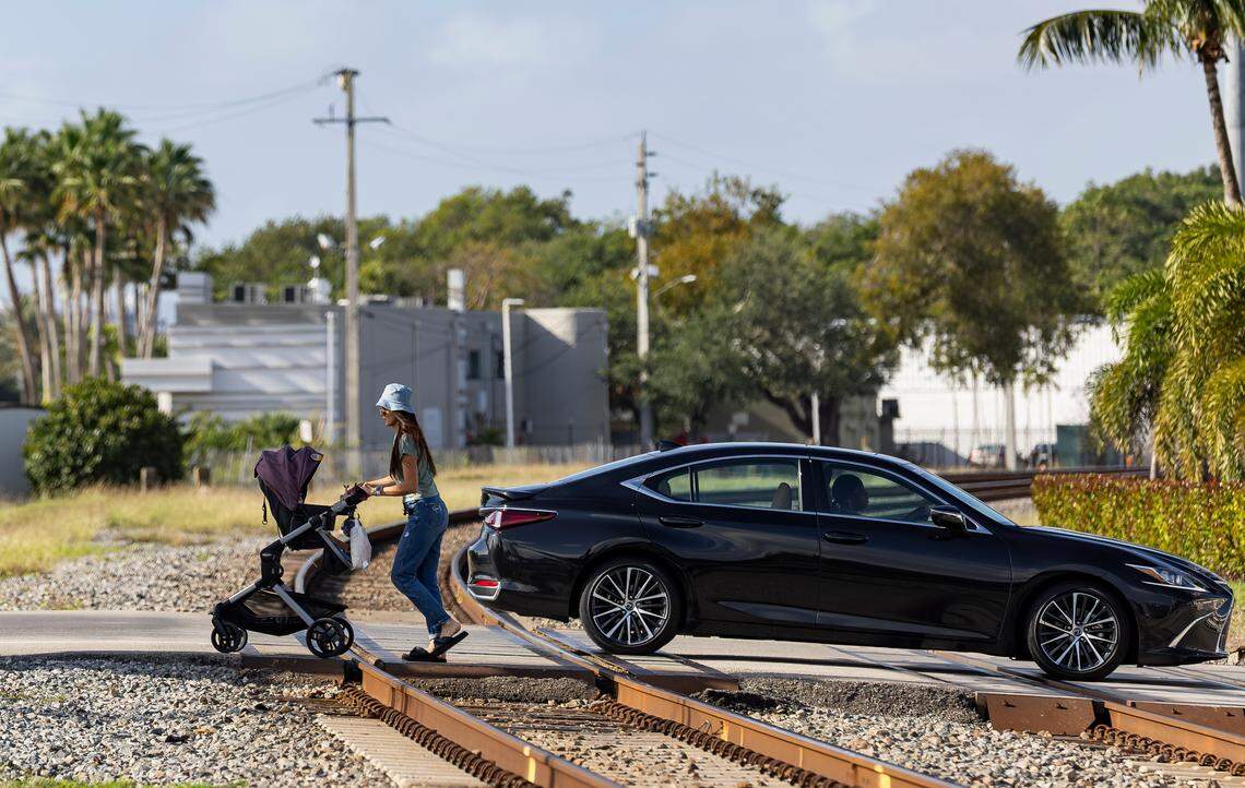 A woman and her daughter cross over train tracks that intersect Northeast 141st Street near Biscayne Boulevard on Wednesday, April 2, 2025, in North Miami, Fla.