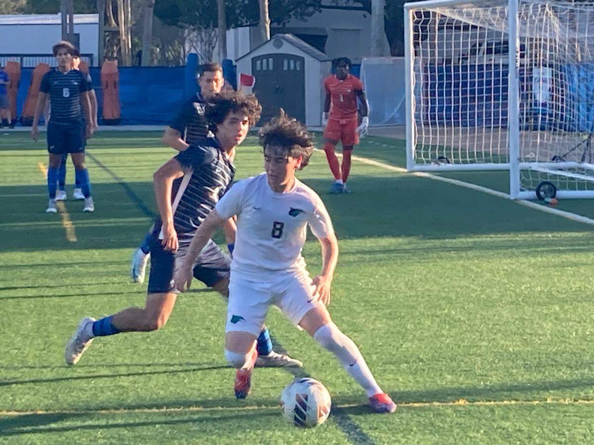 Downtown Doral forward Santiago Ramos (8) tries to maintain control of the ball as University School’s Liam Peirce pursues during Friday’s Region 4-3A semifinal contest at Auto Nation Field.