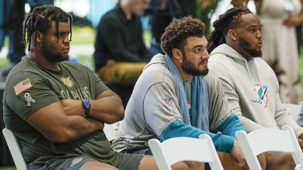 El defensive tackle Kenneth Grant, el tight end Jalin Conyers y el defensive tackle Jordan Phillips (de izq a der.) escuchan al nuevo gerente general Jon-Eric Sullivan y al entrenador Jeff Hafley, durante una conferencia de prensa celebrada el 22 de enero de 2026 en el Baptist Health Training Complex en Miami Gardens, Florida.