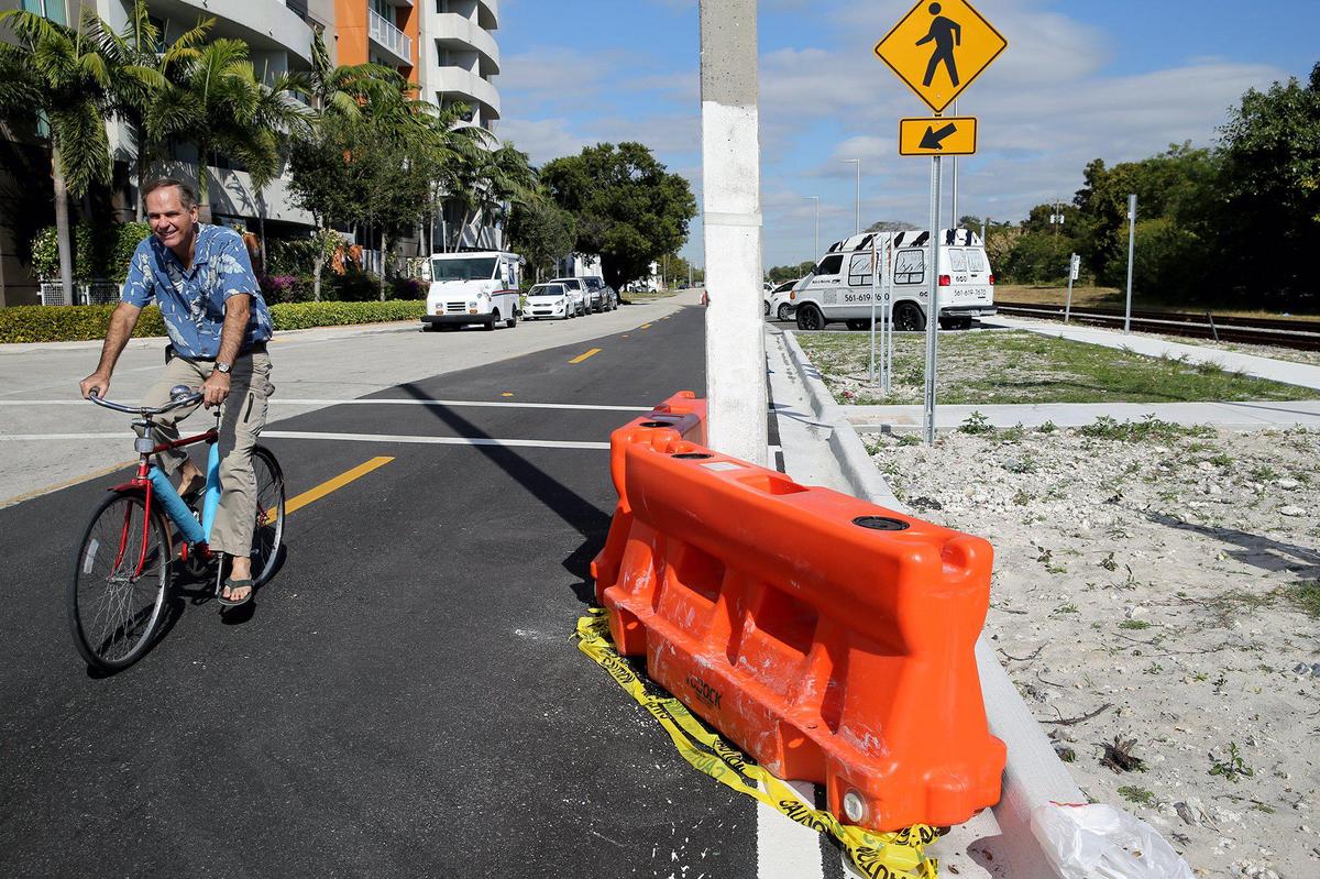 Elvis Cruz rides his bike on Northeast Fourth Avenue past a concrete utility pole that sits in the northbound traffic lane at Northeast 55th Terrace, the result of a flawed improvement project criticized for making the Little Haiti street more dangerous than it was before.