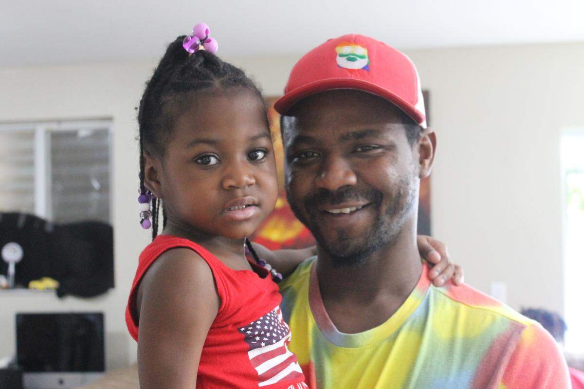 Jermaine Toomer holds his daughter Serenity inside their Homestead house.