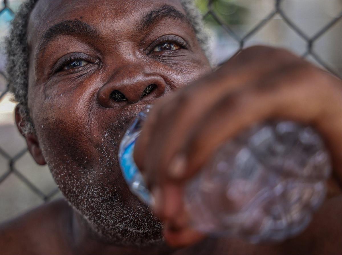 Jean Wilfred, 70, enjoys a bottle of water handed out by the Miami-Dade Homeless Trust’s outreach team on Thursday, Aug. 1, 2024, in Miami, Florida.
