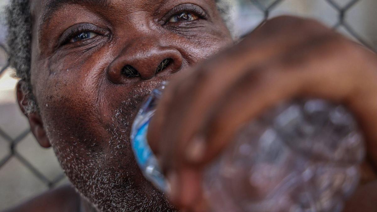 Jean Wilfred, 70, enjoys a bottle of water as the outreach team from the Miami-Dade Homeless Trust hands out bottles of water to individuals living on the street on Aug. 1, 2024, in Miami, Florida, a day that the National Weather Service issued a heat advisory for Miami-Dade.