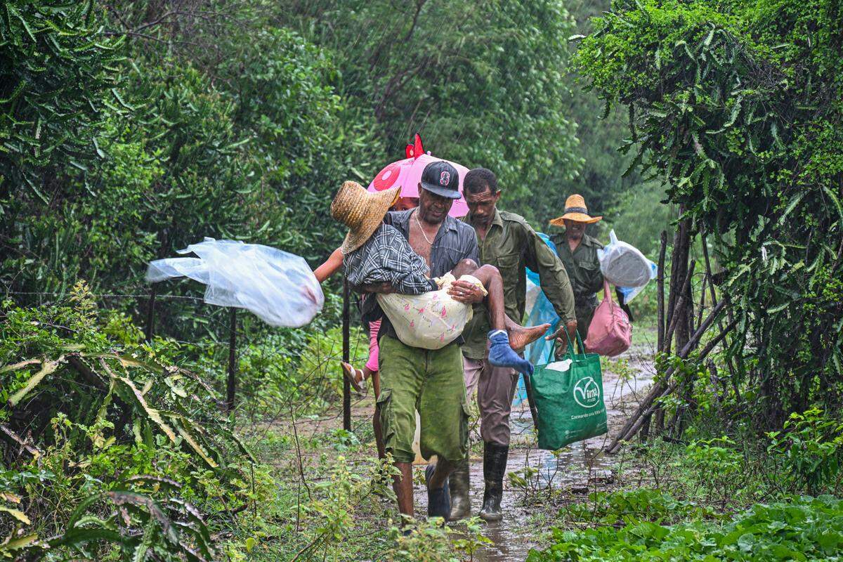 Residentes evacúan bajo una lluvia torrencial desde Playa Siboney a lugares seguros antes de la llegada del huracán Melissa, en Santiago de Cuba, el martes. 