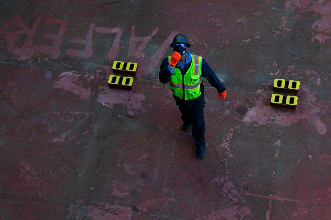 Longshoreman Clyde Sands communicates with the gantry operator as they work to offload a cargo ship at PortMiami on Saturday, February 20, 2021. Sands, a ship flag, has been working as a longshoreman for 28 years.