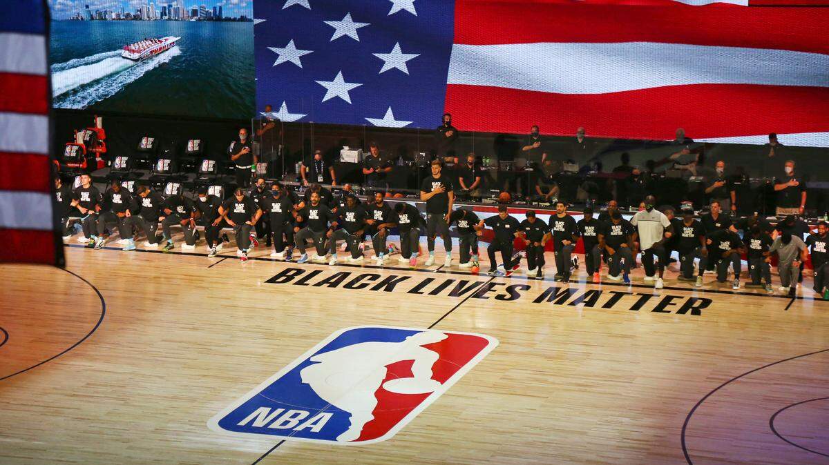 Members of the Boston Celtics and the Miami Heat kneel during the national anthem before an NBA basketball game Tuesday, Aug. 4, 2020, in Lake Buena Vista, Fla.