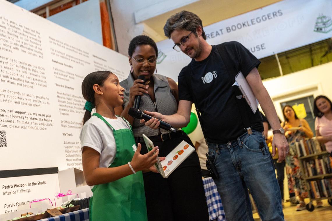 Bookleggers founder Nathan Sandler, right, and award-winning local filmmaker Monica Sorelle, center, hear from contestant Miranda Irribarra, left, as she presents ‘The Very Hungry Caterpillar’ meringue during a Bookleggers ‘bake-off’ at Bakehouse Art Complex on Saturday, July 13, 2024, in Miami, Fla.