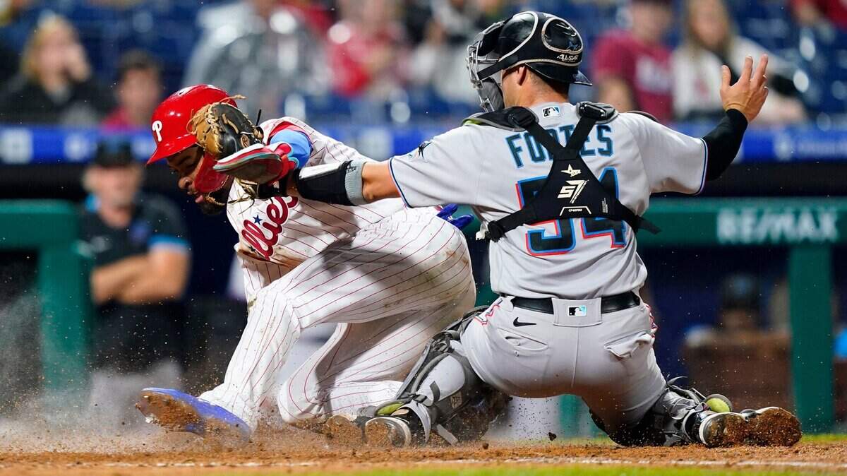 Philadelphia Phillies’ Edmundo Sosa, left, scores against Miami Marlins catcher Nick Fortes on an RBI-sacrifice fly by Alec Bohm during the sixth inning of a baseball game, Tuesday, Sept. 6, 2022, in Philadelphia. (AP Photo/Matt Slocum)