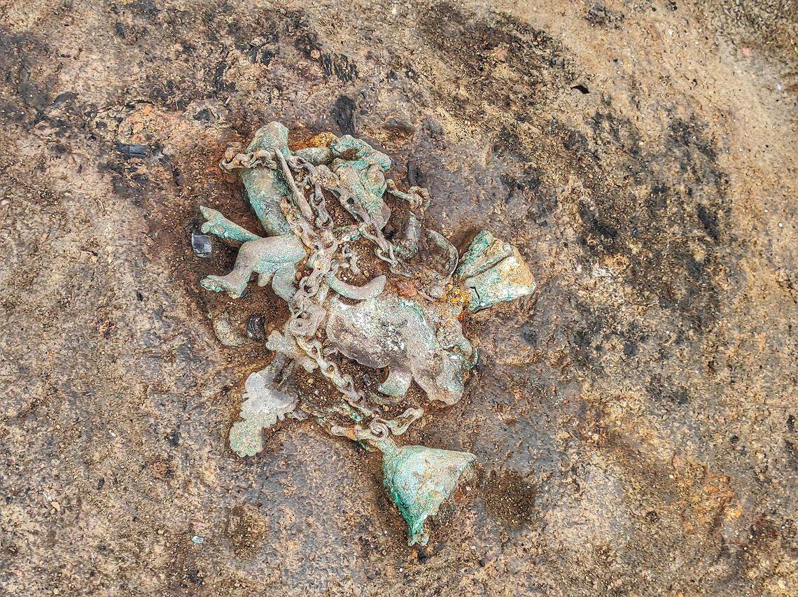 A photo shows the partially excavated tintinnabulum, a “magical” phallus-shaped wind chime.