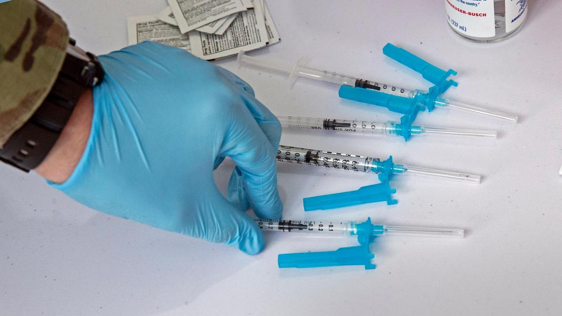 A member of the U.S. military prepares needles for the COVID-19 vaccine to be used during opening day of the FEMA vaccination site on Miami Dade College’s North Campus on Wednesday, March 3, 2021.