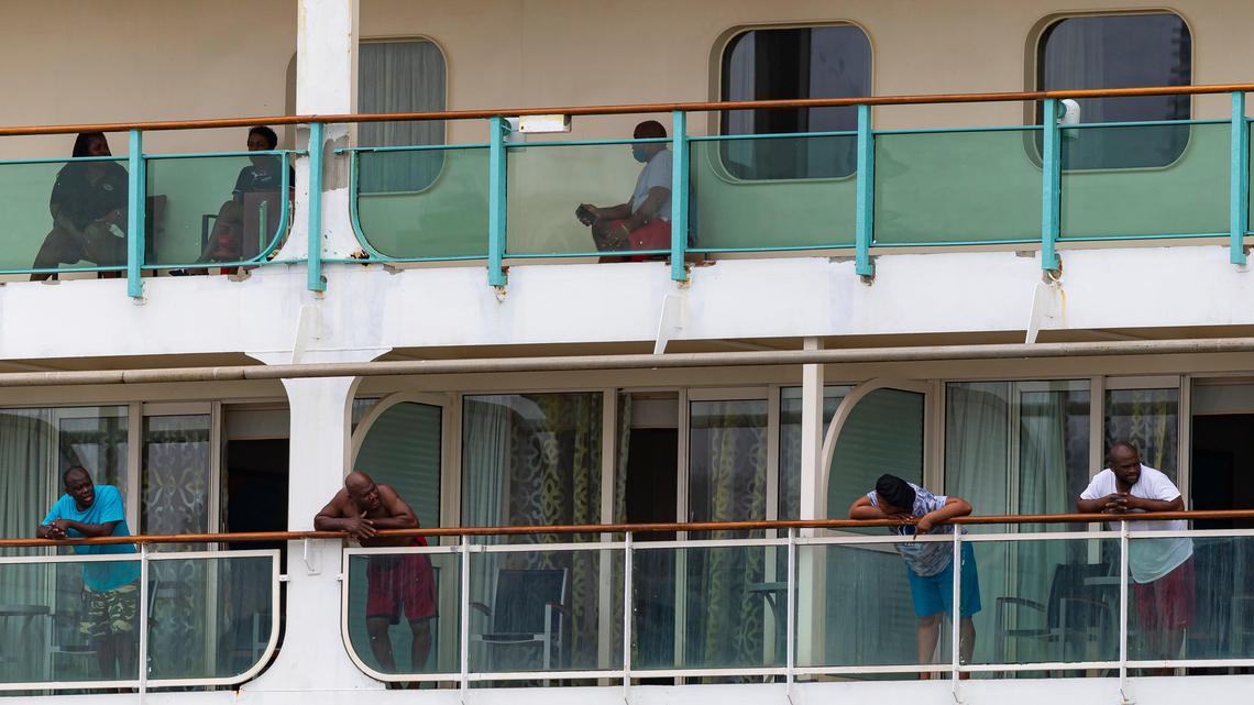 Crew members aboard Royal Caribbean’s Vision of the Seas pass the time on their balconies as the ship is docked at PortMiami on Friday, May 15, 2020, in Miami, Florida.