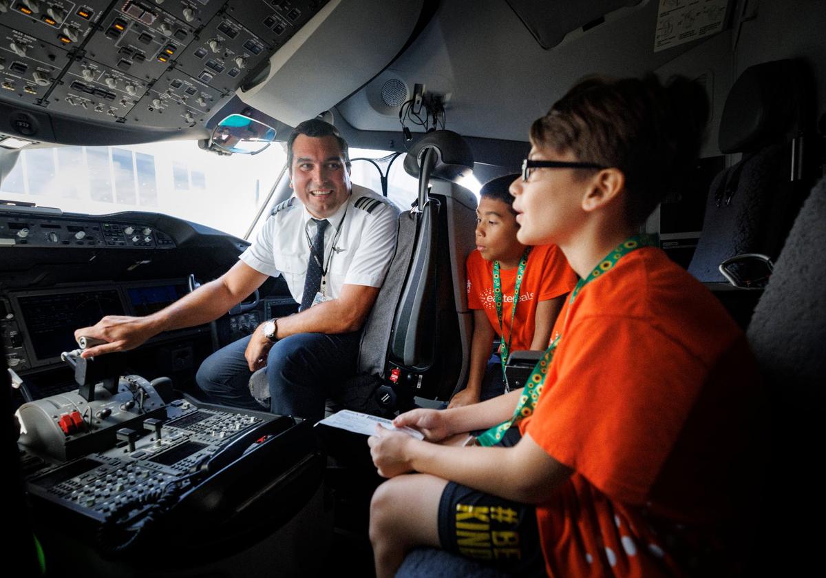 Eli Velez, Miami-based first officer on American Airlines, left, talks to Daniel Espinal, center, and Kyler Silva, in the cock pit during an airport readiness drill with Easterseals South Florida kids to prepare them for experiencing air travel on Tuesday, July 23, 2024, at Miami International Airport. Many of the kids have autism or other disabilities that can make airports stressful, so this tour showed them what it was like.