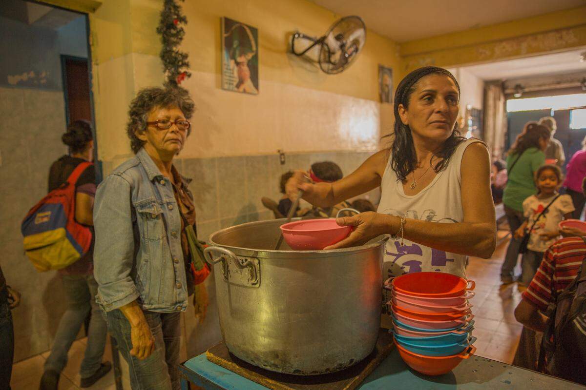 In the dining room of Casa de Maria, cook Livia Madueño is busy serving soup. She gives out 350 bowls each day.