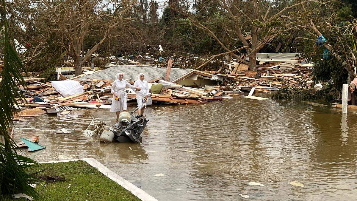 The morning after Hurricane Ian brought catastrophic storm surge, two Poor Clare sisters walk through the parking lot amid the destruction in front of their monastery and Ascension Parish on Fort Myers Beach on Sept. 29, 2022. The debris pile included the contents of at least four homes.