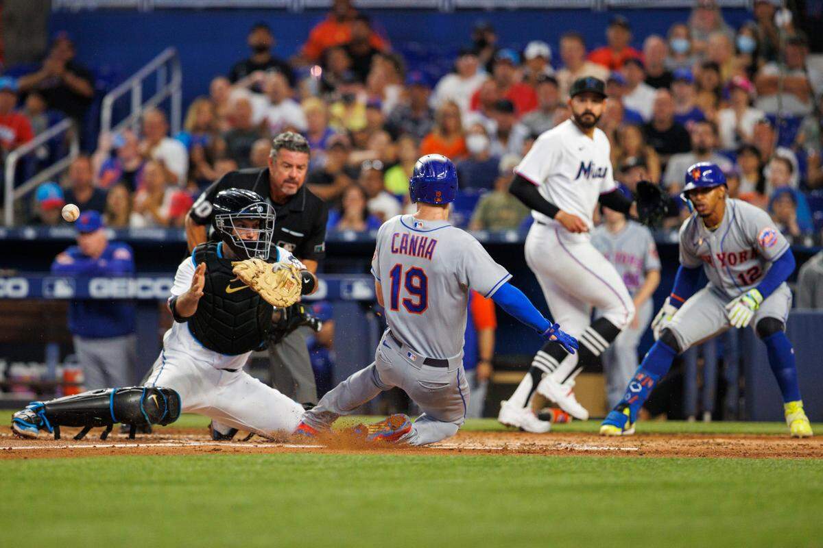 New York Mets left fielder Mark Canha (19) slides safety into home plate as Miami Marlins catcher Jacob Stallings (58) is unable to apply a tag during the third inning of a baseball game at LoanDepot Park on Sunday, July 31, 2022 in Miami, Florida.