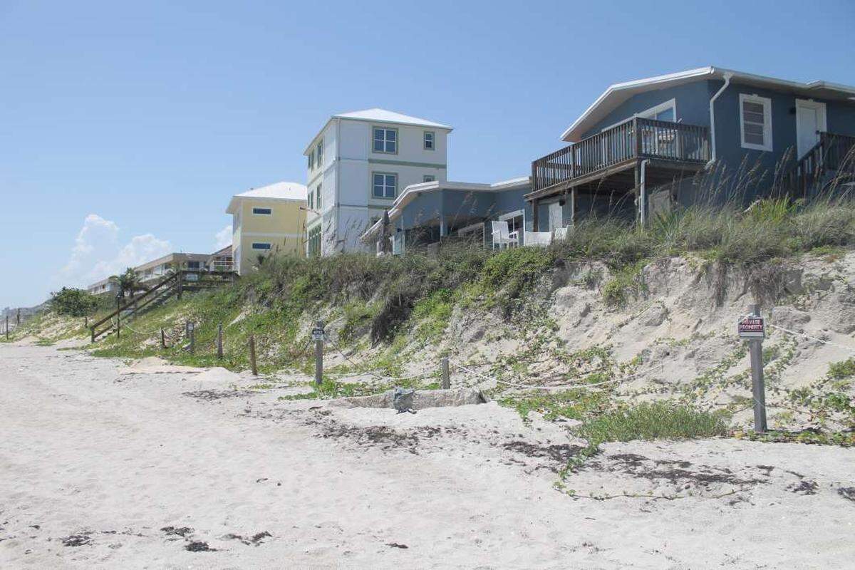 In Satellite Beach homes perch atop a sand dune, left exposed after a series of storms and hurricanes washed away a sea wall.