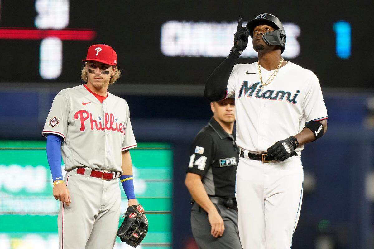 Miami Marlins’ Jorge Soler, right, reacts after hitting a double during the first inning of a baseball game against the Philadelphia Phillies, Friday, April 15, 2022, in Miami. Phillies second baseman Bryson Stott, left, looks on.