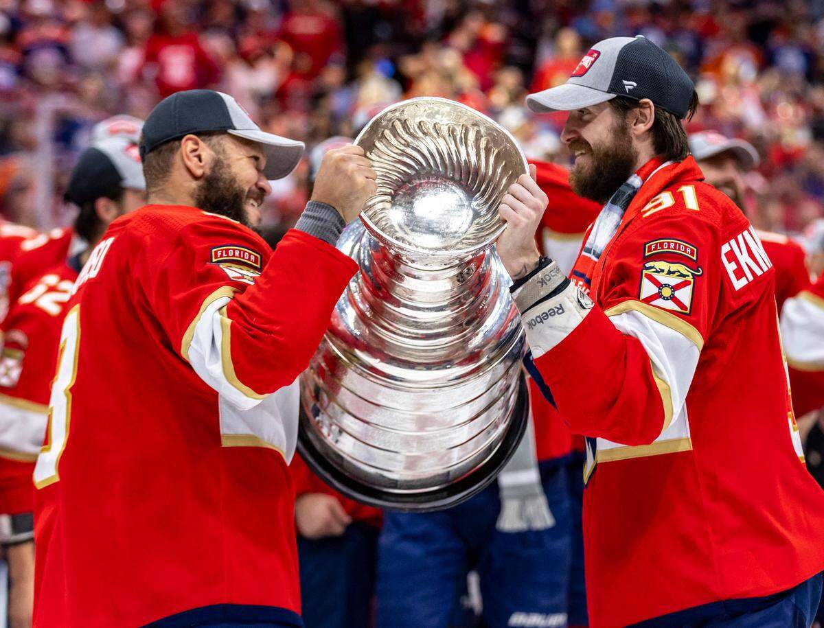 Sunrise, Florida, June 24, 2024 - Florida Panthers right wing Kyle Okposo (8) hands the Stanley Cup to Oliver Ekman-Larsson (91) as they celebrate their victory over the Edmonton Oilers.