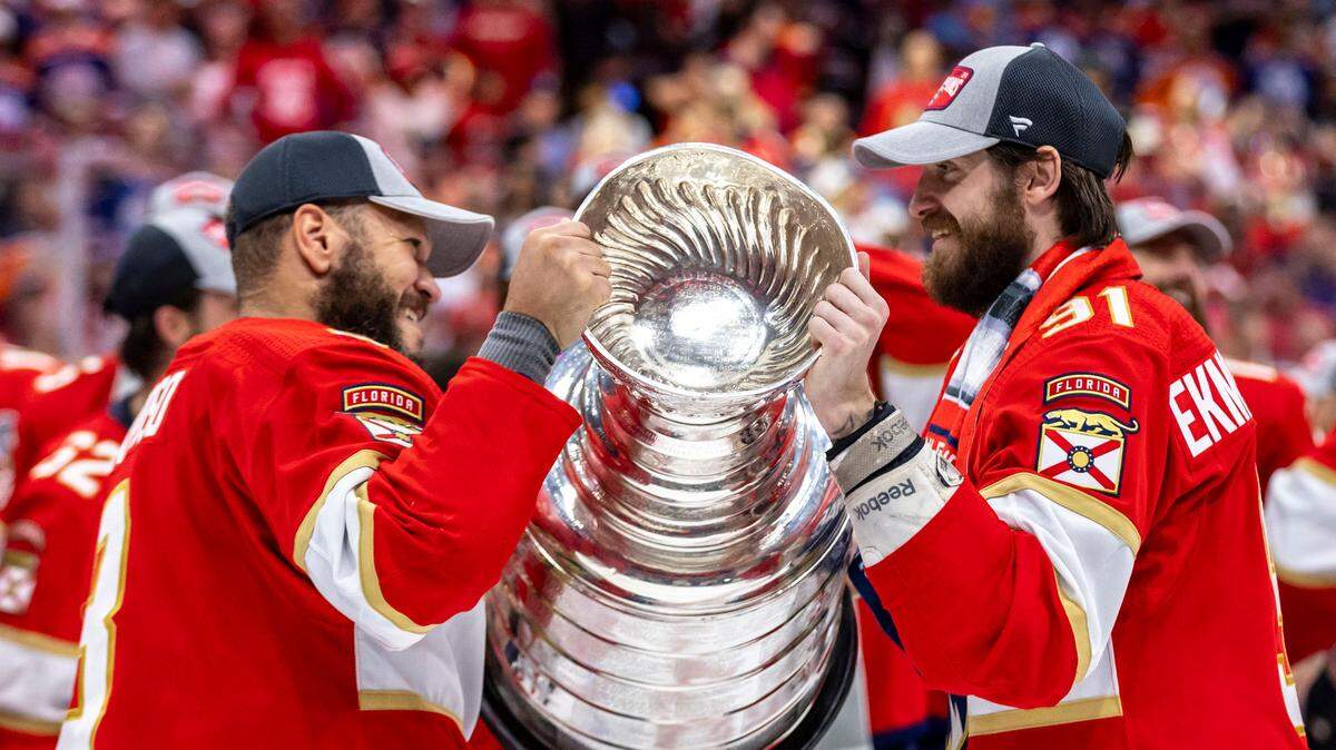 Sunrise, Florida, June 24, 2024 - Florida Panthers right wing Kyle Okposo (8) hands the Stanley Cup to Oliver Ekman-Larsson (91) as they celebrate their victory over the Edmonton Oilers.