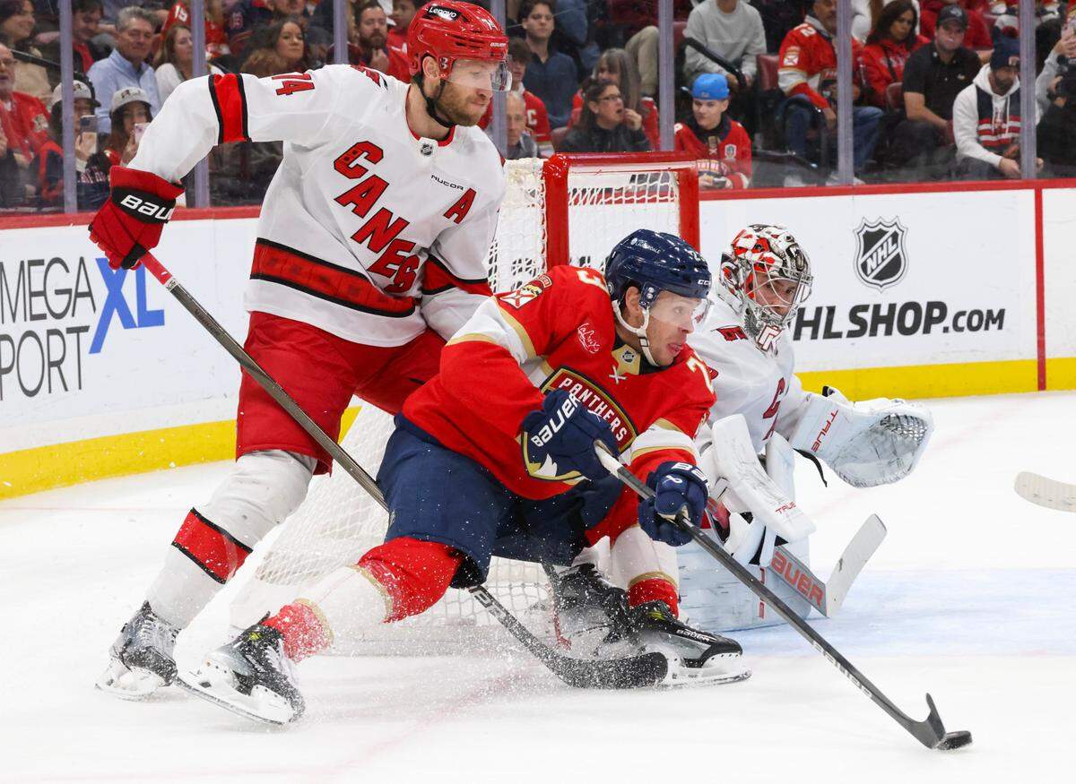 Florida Panthers center Carter Verhaeghe (23) keeps the puck from Carolina Hurricanes defenseman Jaccob Slavin (74) and goaltender Pyotr Kochetkov (52) during the second period of a game on Thursday, Jan. 2, 2025, at Amerant Bank Arena in Sunrise, Fla.