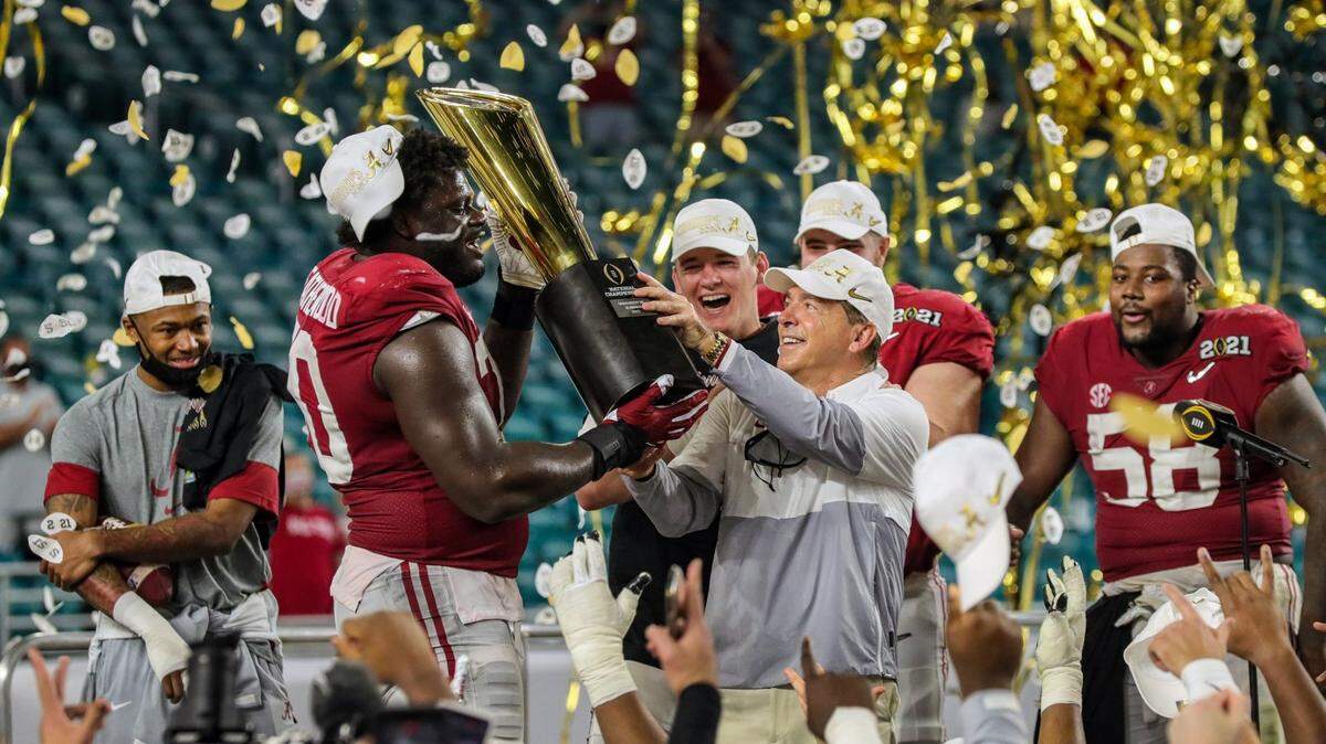 Alabama Crimson Tide head coach Nick Saban and offensive lineman Alex Leatherwood (70) hold the championship trophy after defeating the Ohio State Buckeyes during the 2021 National Championship game at Hard Rock Stadium in Miami Gardens on Tuesday, January 12, 2021.
