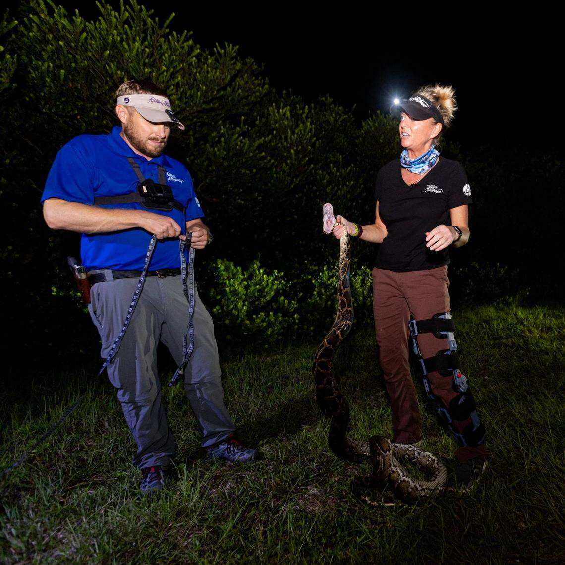 Python Huntress Amy Siewe holds an invasive 10-foot Burmese Python originally caught by Harold Antonio Rondon-Mena while her partner Dave Roberts prepares to measure the snake during a hunting trip down Tamiami Trail on Thursday, September 5, 2024, in Miami, Fla.