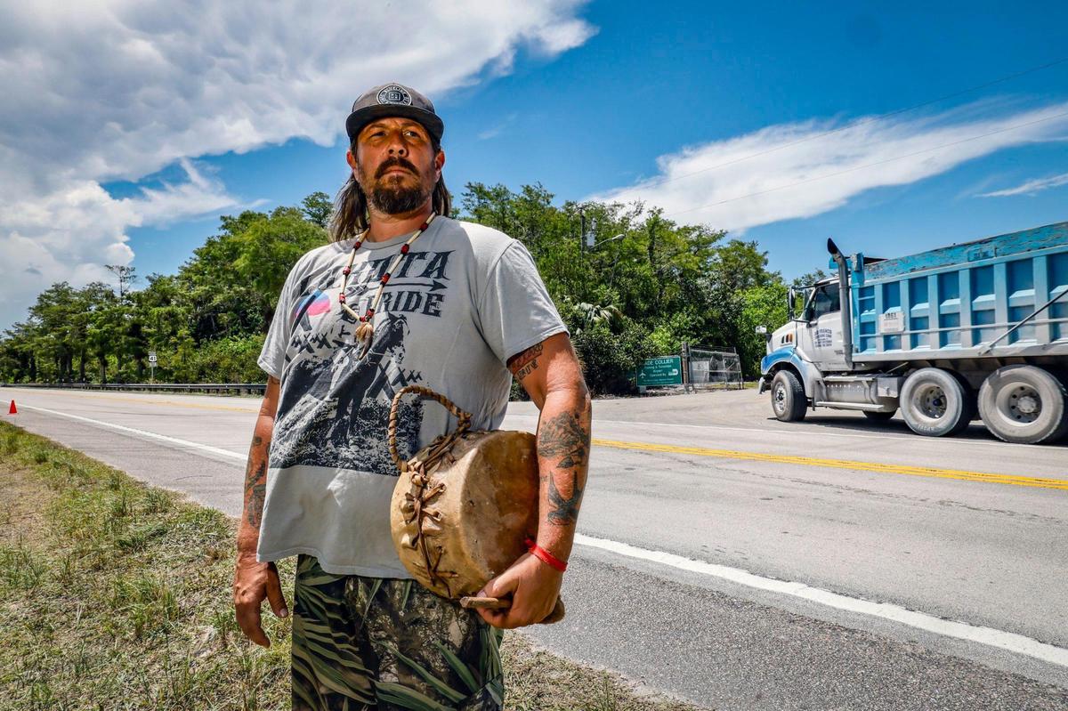 Garrett Stuart, who is of Lakota descent, stands outside in protest as he watches trucks arrive at the front gates to Alligator Alcatraz off Highway 41. He lives about three miles away in a Miccosukee village.