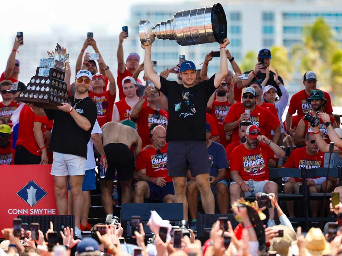 Florida Panthers center Sam Bennett hoists the Conn Smythe Trophy while captain Aleksander Barkov lifts the Stanley Cup as teammates celebrate on stage during the team’s victory parade and rally along A1A in Fort Lauderdale, Florida, on Sunday, June 22, 2025