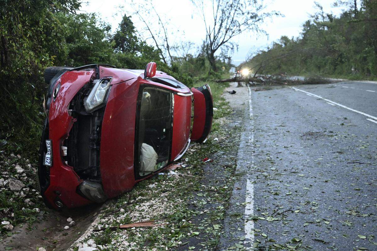 A damaged car by a fallen tree is seen after the passage of Hurricane Melissa in Manchester, Jamaica, on October 28, 2025. Hurricane Melissa ripped up trees and knocked out power after making landfall in Jamaica on October 28, 2025 as one of the most powerful hurricanes on record, inundating the island nation with rains that threaten flash floods and landslides. (Photo by Ricardo Makyn / AFP) (Photo by RICARDO MAKYN/AFP via Getty Images)
