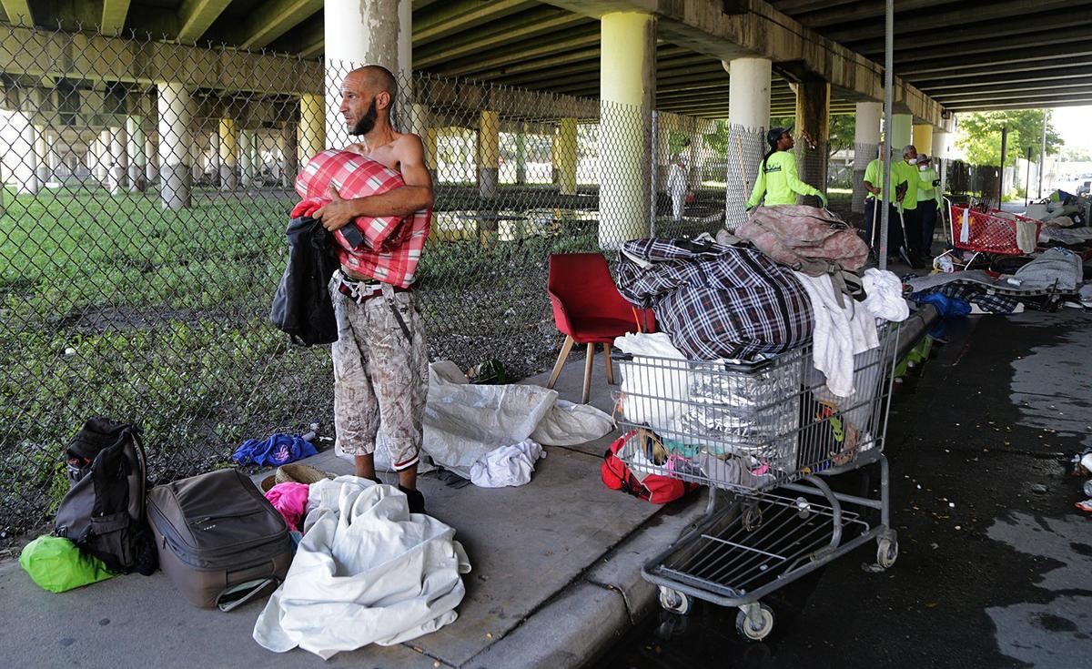 Carlos Pino, a homeless man, packs his belongings before heading to a shelter with the assistance of city workers. “It’s hell out here,” he told a reporter.