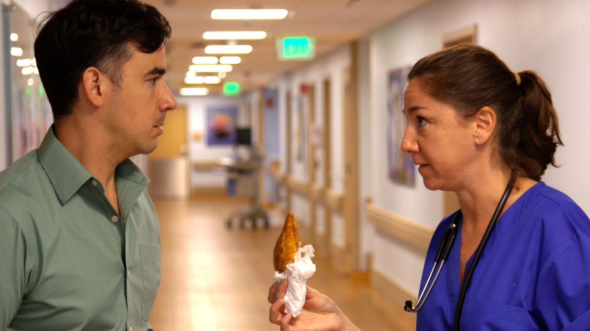 A comedic scene from the The Plantain’s commercial spot for Jackson Health System’s maternity ward in Miami. The nurse, played by Rachel Biderman, sneaks a pastelito to nervous dad, played by Nick Ducassi.
