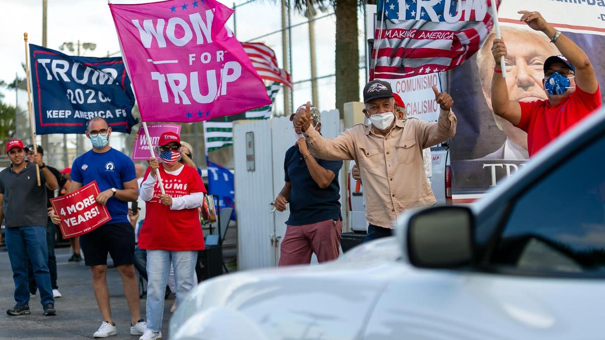 Seguidores del presidente Donald Trump saludan a los votantes cuando llegan a la Biblioteca John F. Kennedy Library en Hialeah, Florida, el martes 3 de noviembre de 2020.