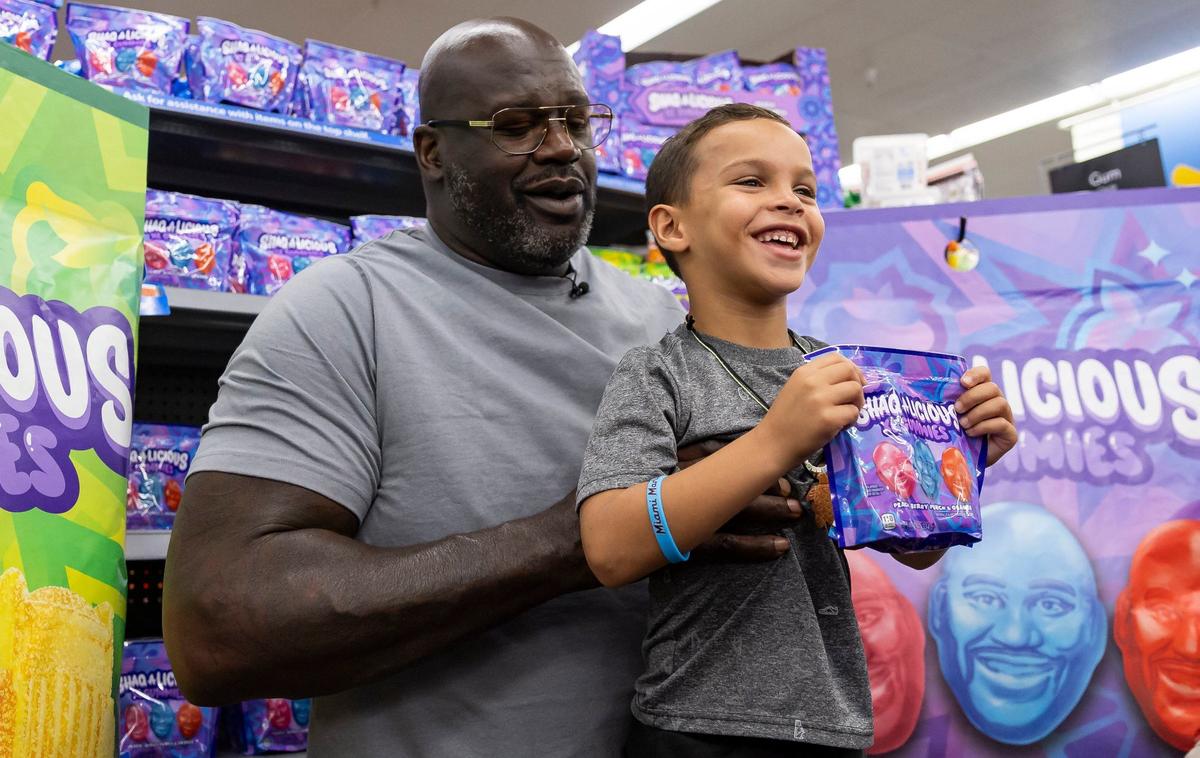 Former Miami Heat player Shaquille O’Neal lifts Kai Gonzalez, 5, as he holds a bag of Shaq-a-licious gummies during its launch event at a Walmart on Monday, Aug. 12, 2024, in Doral, Fla. To promote the candy, O’Neal attended the event while giving free bags of gummies to shoppers.