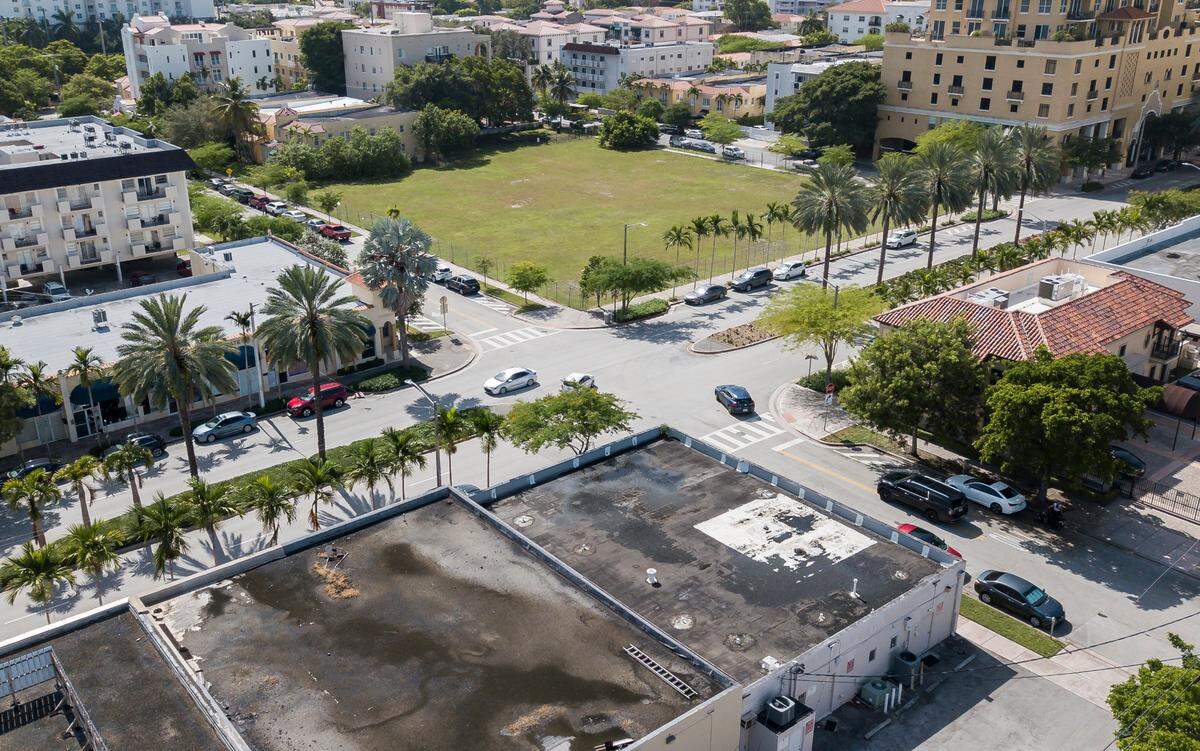 An aerial view of the grassy lot located at 1505 Ponce de Leon Blvd. on Monday, Aug. 14, 2023, in Coral Gables, Fla. A Location Ventures-related entity purchased the lot for about $35.5 million late last year, with plans to build a luxury condo tower on the land. Last summer, developer Rishi Kapoor began renting the building directly across the street, bottom center, from Coral Gables Mayor Vince Lago, with plans to use it as a sales center showroom for the 1505 Ponce project.