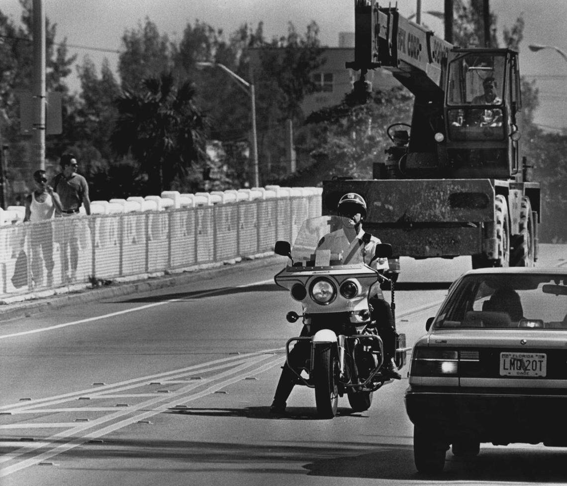 Miami Beach police motorcycle officers stop traffic to escort heavy vehicles across the Venetian Causeway in 1993.