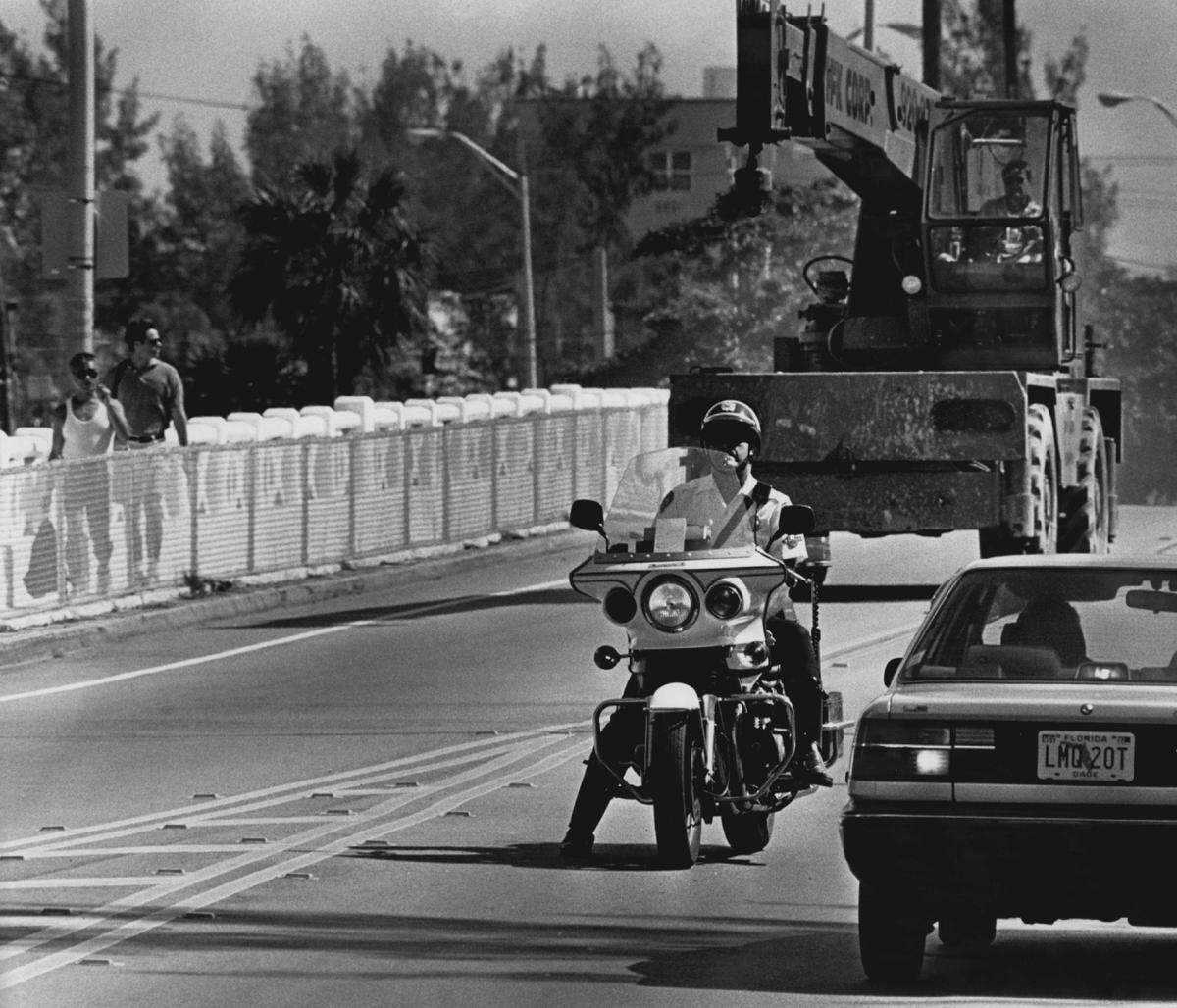 Miami Beach police motorcycle officers stop traffic to escort heavy vehicles across the Venetian Causeway in 1993.